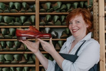 Saskia Wittmer in ihrer Florentiner Werkstatt mit fertigem rahmengenähtem Maßschuh und der Sammlung von Kundenleisten