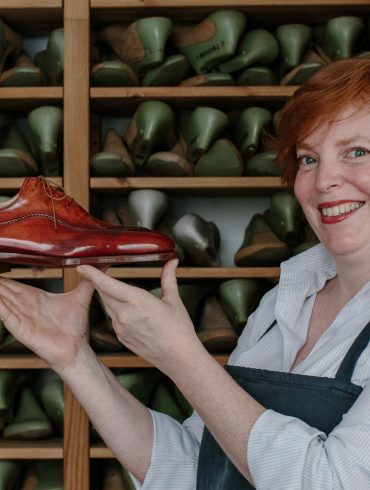 Saskia Wittmer in ihrer Florentiner Werkstatt mit fertigem rahmengenähtem Maßschuh und der Sammlung von Kundenleisten