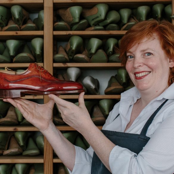 Saskia Wittmer in ihrer Florentiner Werkstatt mit fertigem rahmengenähtem Maßschuh und der Sammlung von Kundenleisten