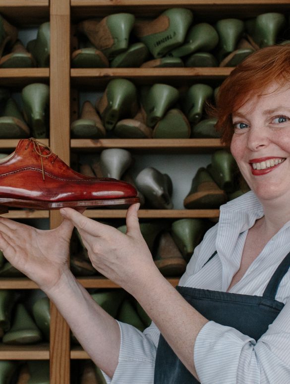Saskia Wittmer in ihrer Florentiner Werkstatt mit fertigem rahmengenähtem Maßschuh und der Sammlung von Kundenleisten