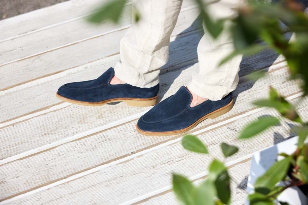 Dunkelblauer Loafer von Crockett & Jones vor grünem Hintergrund