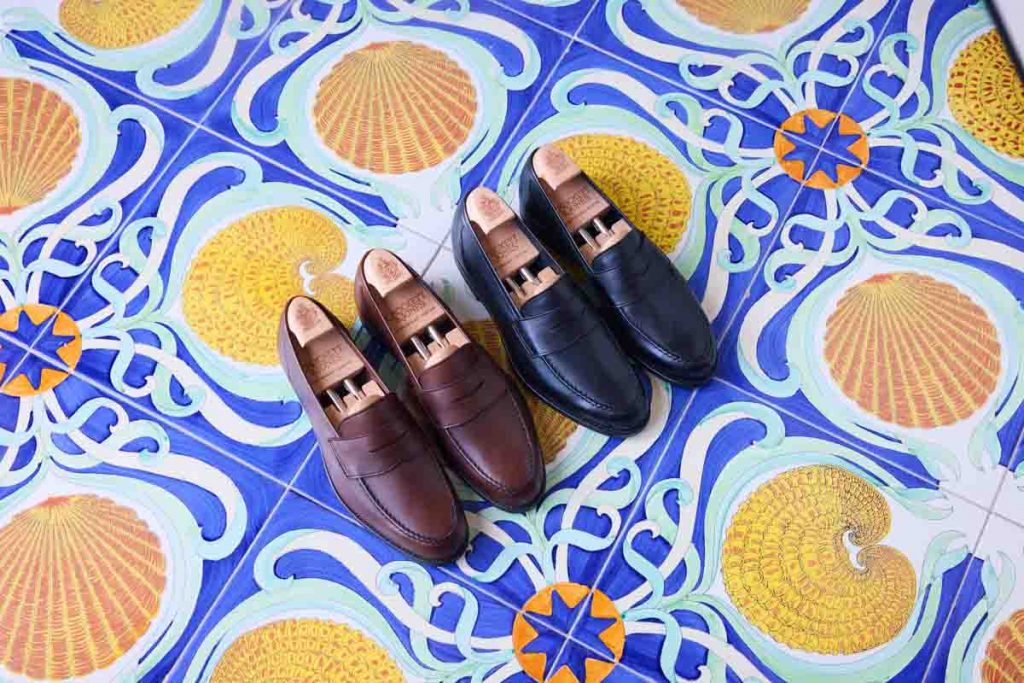 Zwei Loafer von Crockett & Jones auf blau-gelben Majolikafliesen