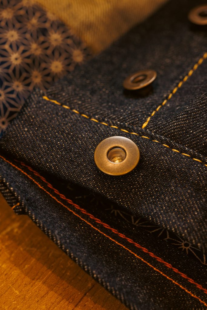 Kupferner Nietknopf an der Gesäßtasche mit oranger Steppnaht