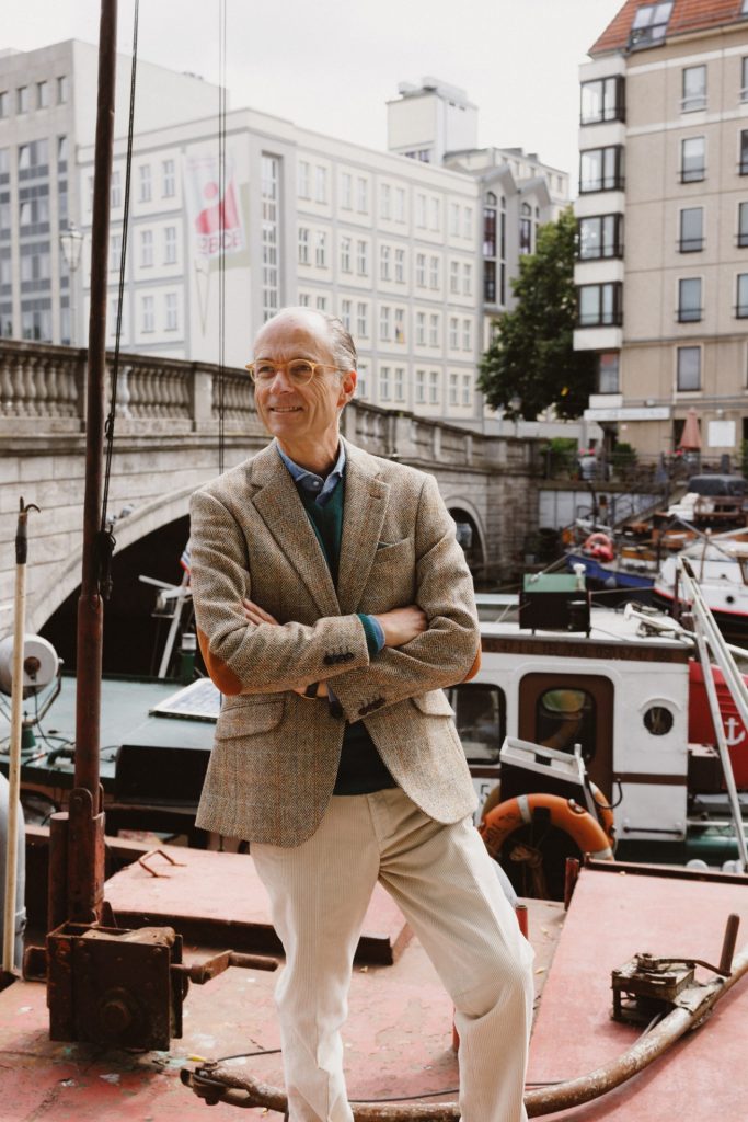 Harris-Tweed-Sakko, tannengrüner Pullover und ecrufarbene Kordhose auf dem Deck des Lastkahns