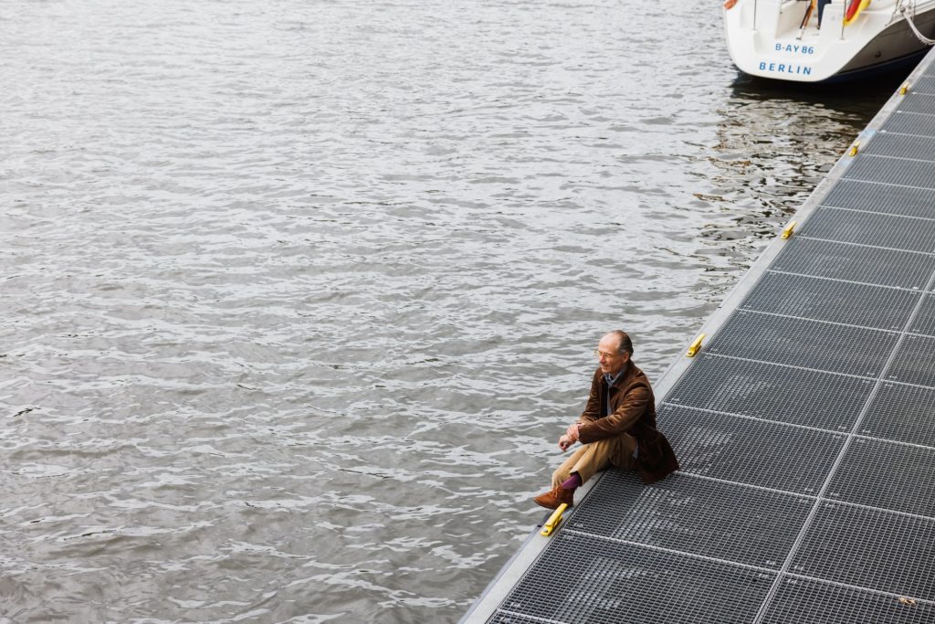 Weite Aufnahme: Figur am Rand eines schwimmenden Stegs an der Spree
