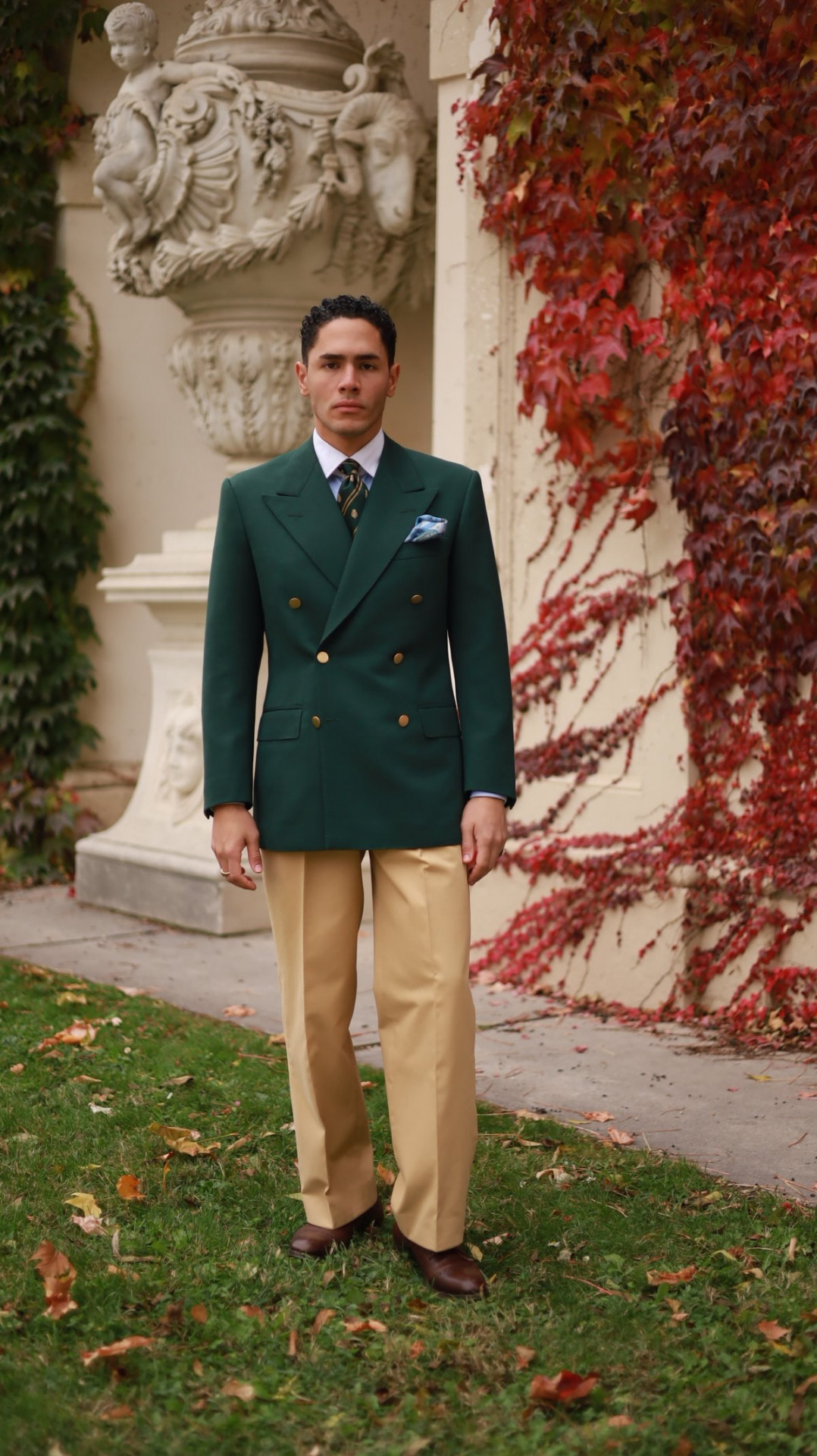 Yasin Tarabia in grünem Sakko und heller Hose vor rotem Herbstlaub