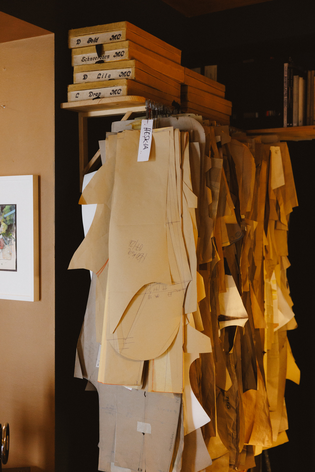 Zugeschnittene Schnittteile aus Papier hängen an einer Stange im Atelier