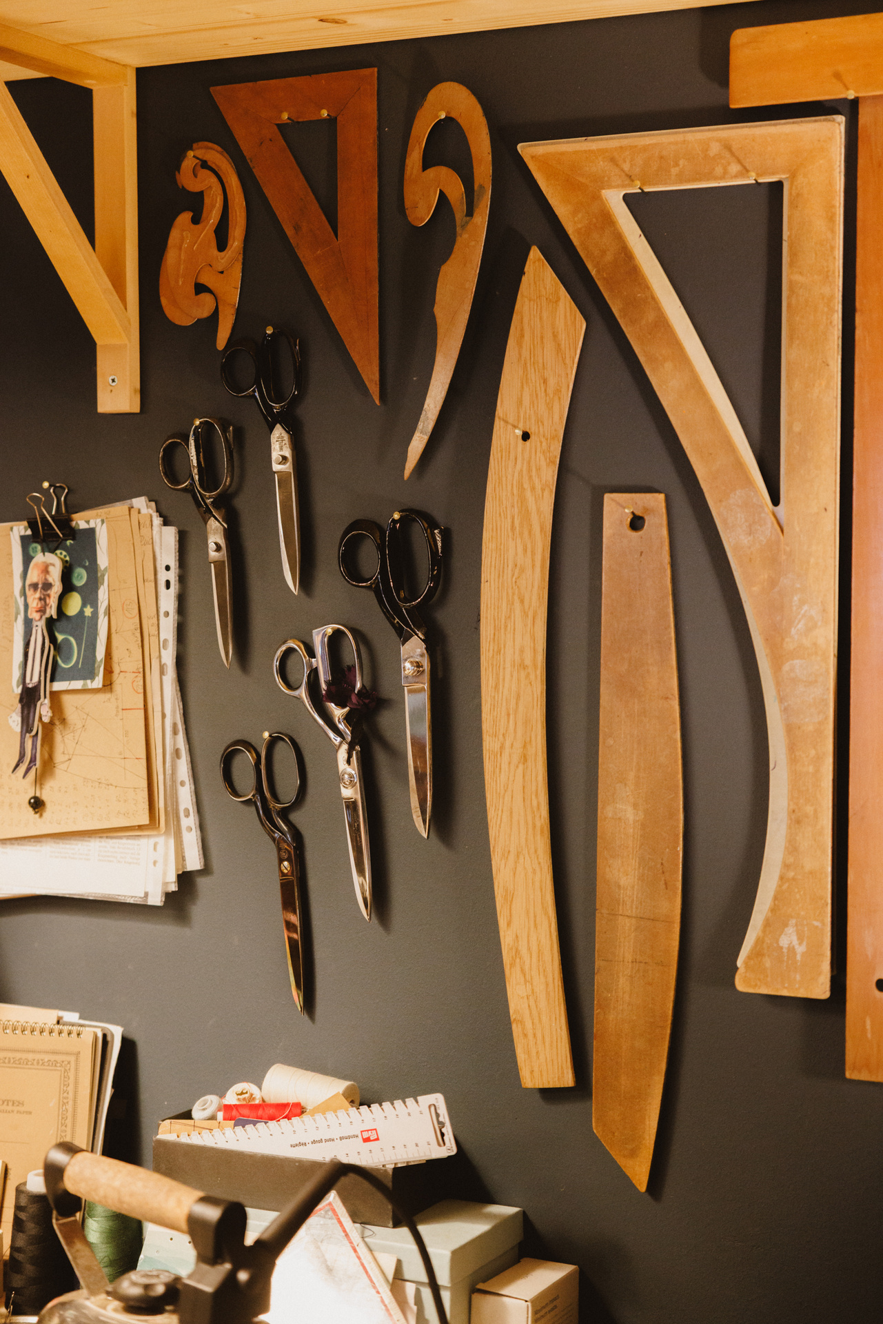 Hölzerne Kurvenlineale und Schneiderscheren an der Atelierwand