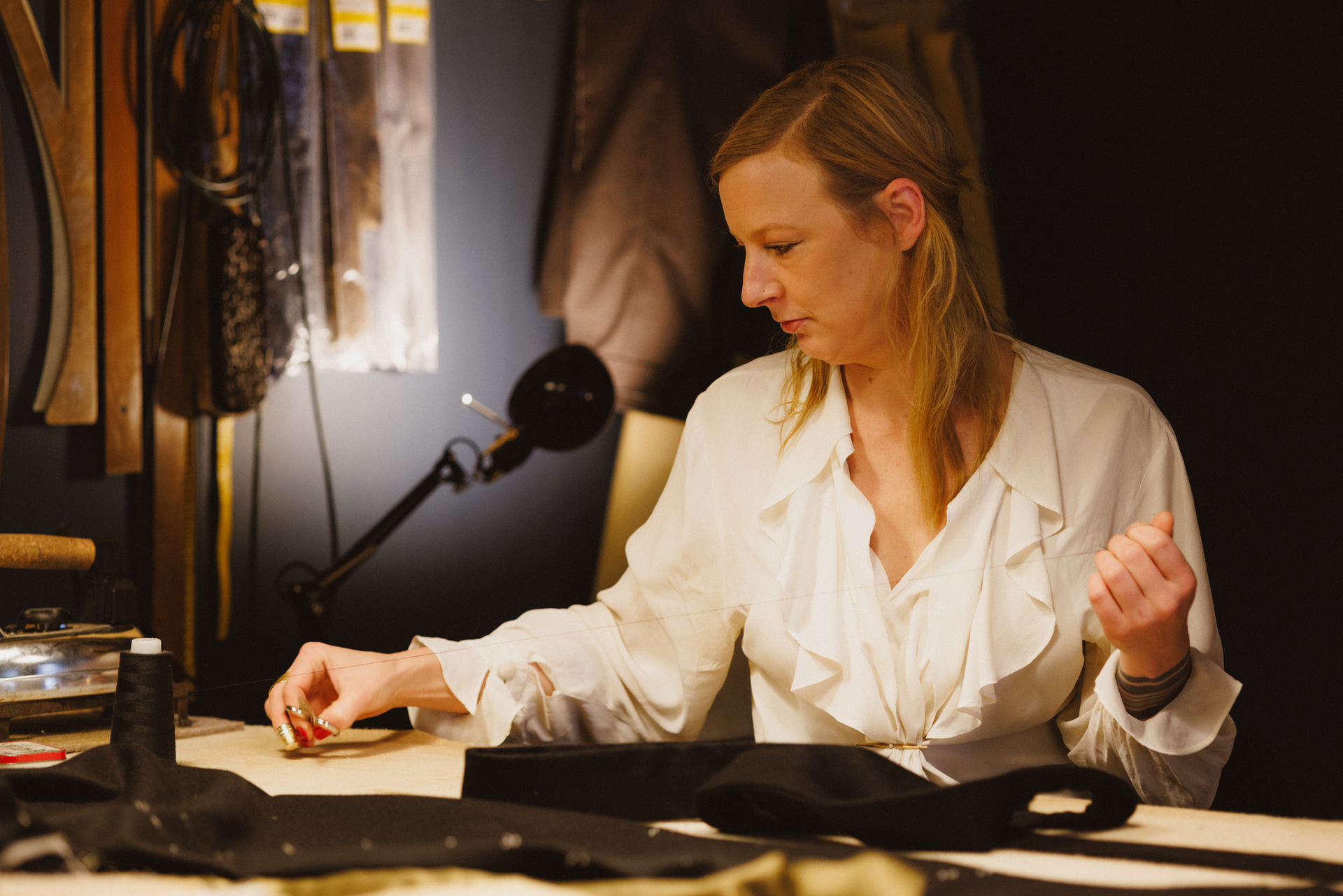 Manuela Leis arbeitet am Zuschneidetisch unter der Lampe