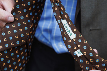 Das Etikett von Drake's auf der Rückseite einer braunen Krawatte mit kleinem Blumenmuster