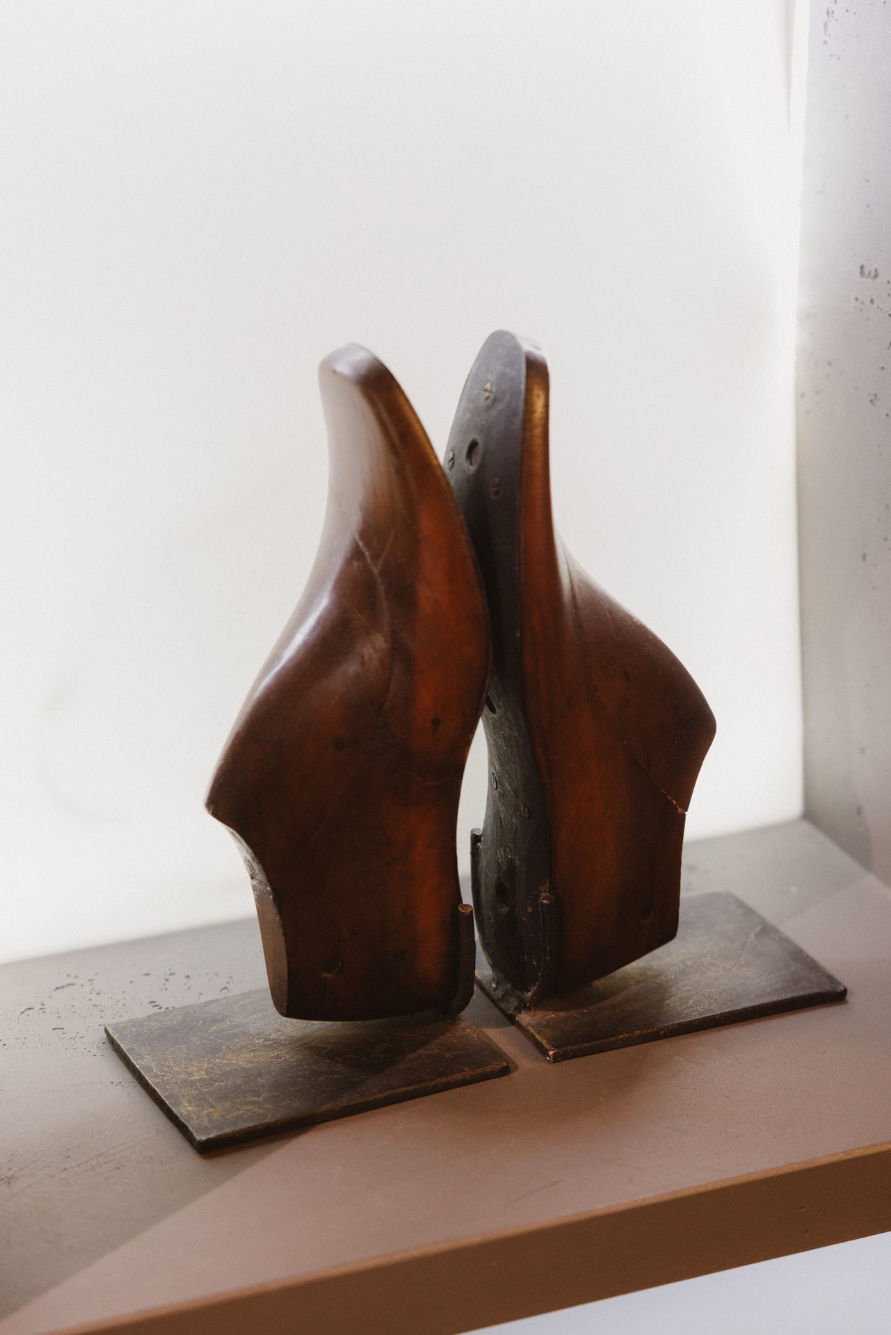 Zwei hölzerne Schuhleisten auf einem Sockel im Verkaufsraum von Schuh Konzept