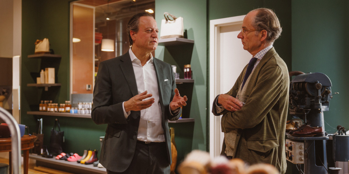 Udo Robakowski im Gespraech mit Bernhard Roetzel im Ladengeschaeft von Schuh Konzept in Berlin, im Hintergrund Regale mit Pflegemitteln und eine Ausputzmaschine