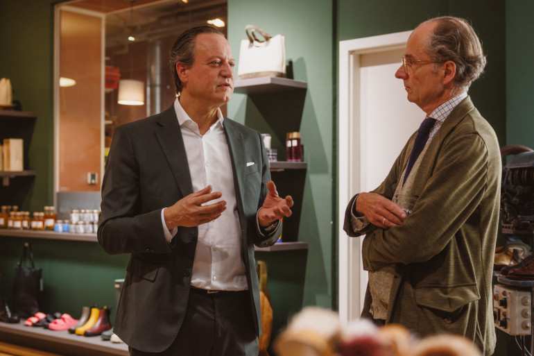 Udo Robakowski im Gespraech mit Bernhard Roetzel im Ladengeschaeft von Schuh Konzept in Berlin, im Hintergrund Regale mit Pflegemitteln und eine Ausputzmaschine