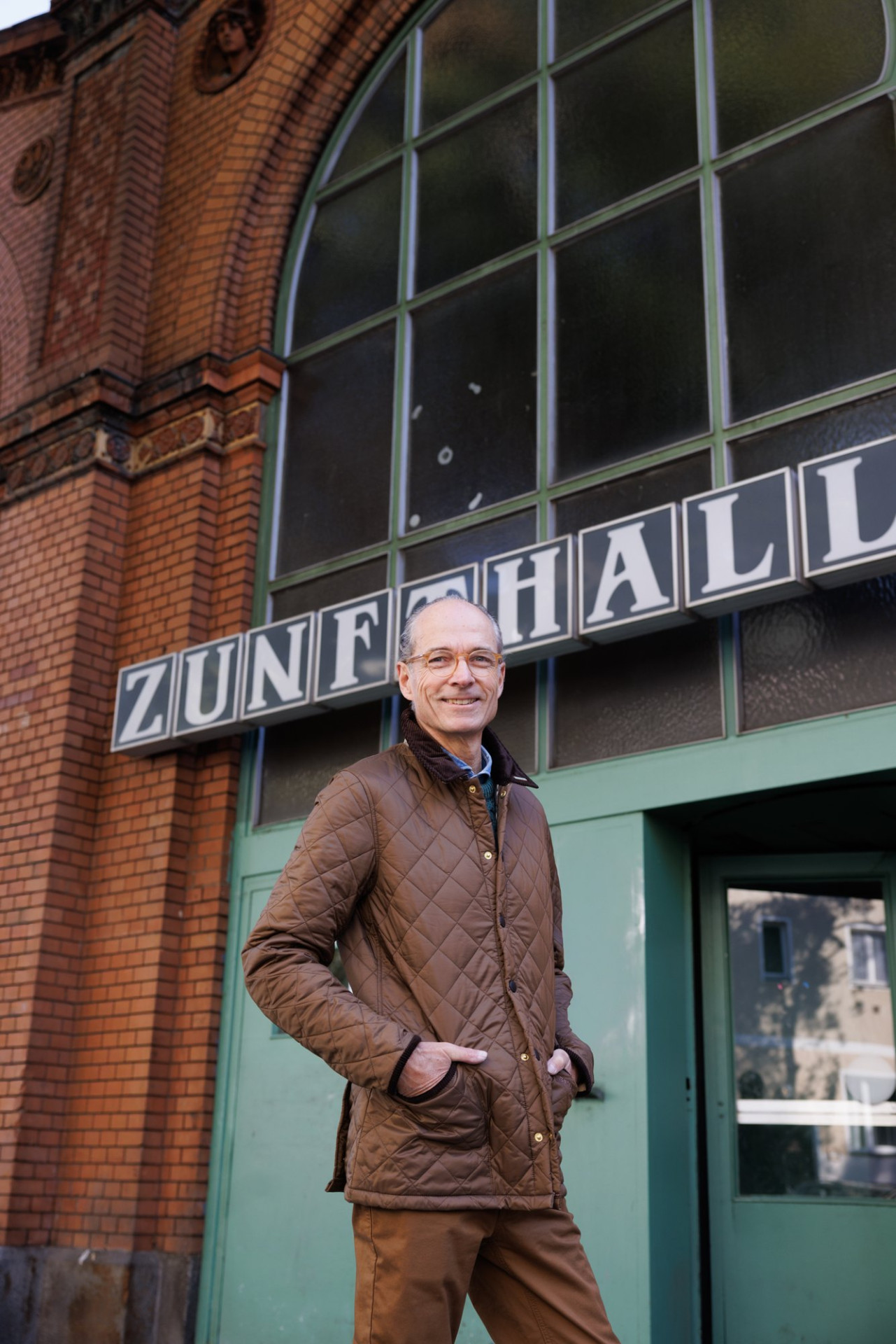 Bernhard Roetzel in der Steppjacke vor dem Eingang der Markthalle, über ihm der Schriftzug