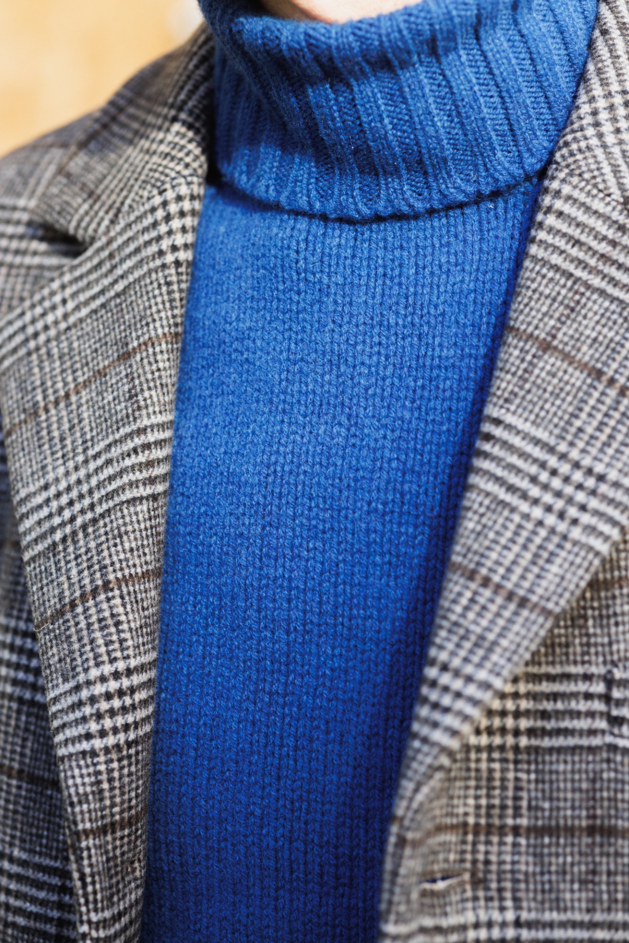 Nahaufnahme des Reverses der Sakkojacke im Prince-of-Wales-Check über dem blauen Turtleneck