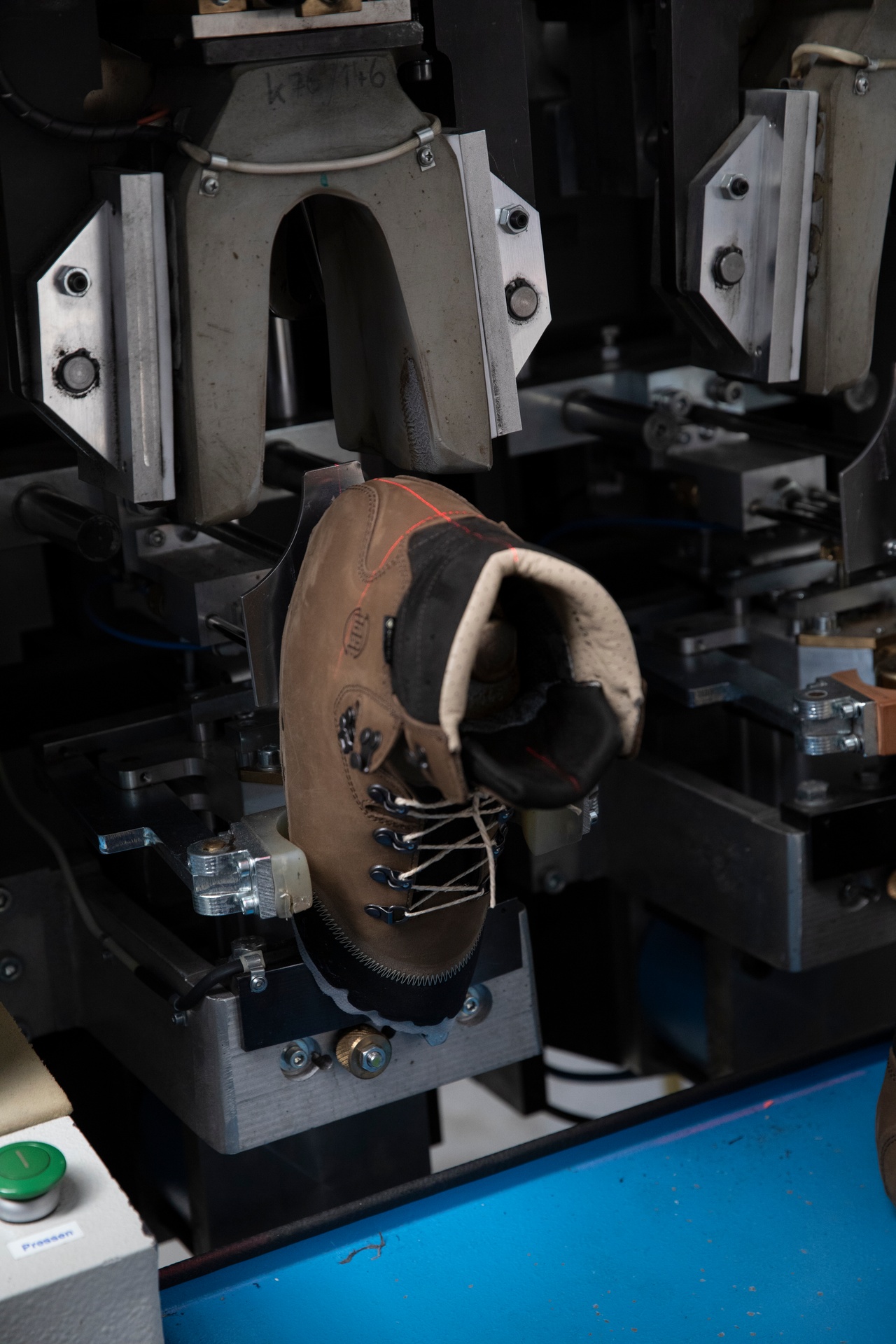 Ein brauner Bergstiefel steckt in einer Zwickmaschine