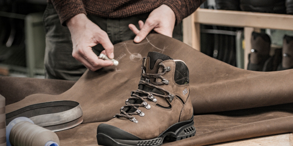 Brauner Hanwag-Bergstiefel auf einer Lederhaut, darüber zeichnet ein Mitarbeiter mit Kreide an