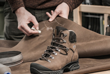 Brauner Hanwag-Bergstiefel auf einer Lederhaut, darüber zeichnet ein Mitarbeiter mit Kreide an