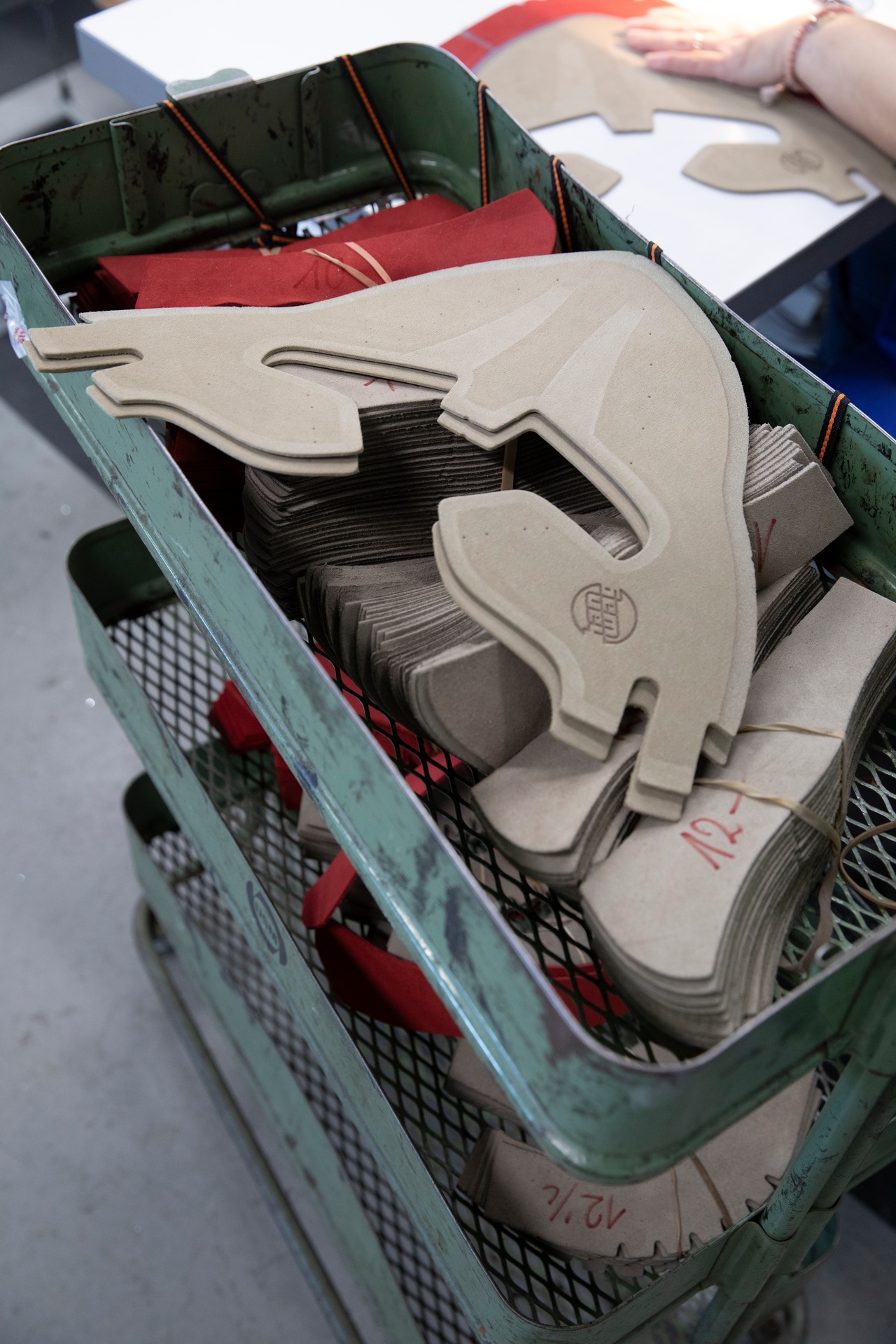 Ein Wagen voller zugeschnittener Schaftteile aus hellem Material und rotem Futter